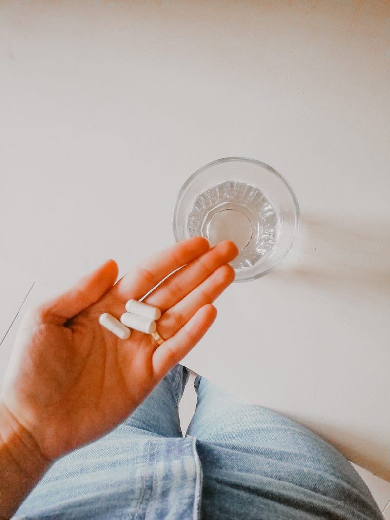 Hand holding pills against a bright background.