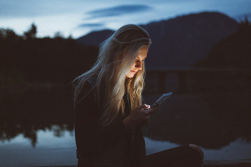 Reflection of a person looking in a mirror after late-night phone use.